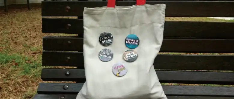たくさんのオリジナルデザインの缶バッジをつけたバッグ